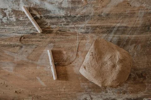 Piece of clay cut with string lying on wooden table prepared for pottery whee Stock Photos