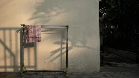 A piece of cloth with a red checkered pattern is dried on a clothesline . Stock Photos