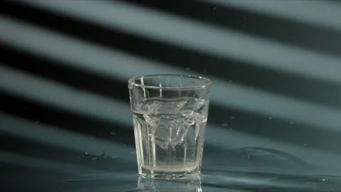 Piece of crushed ice falls into transparent glass with clean drinking water, on Stock Footage 167664191