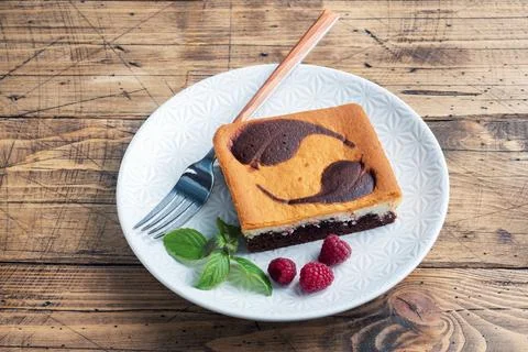 A piece of double-layer cake on a plate of chocolate brownies and curd chee.. Stock-Fotos