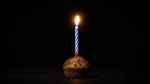 A piece of a festive cake with a burning candle. Chocolate cake on a black ba Stock-Footage 85458519