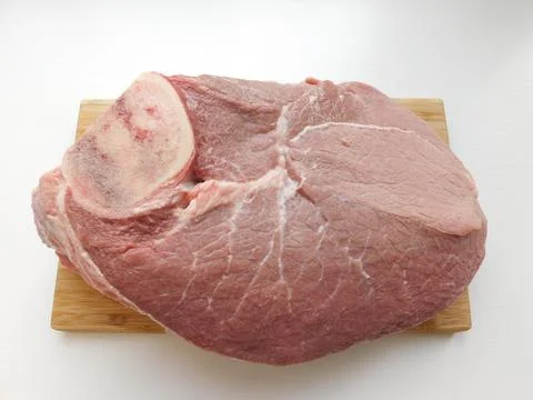 A piece of fresh beef with a bone on a white wooden table Stock Photos