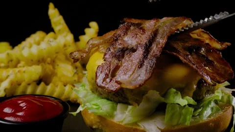 A piece of fried bacon placed on a burger Stock Footage 262853312