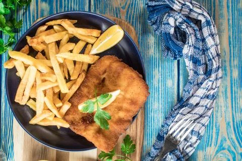 A piece of fried cod with fries on a plate. Stock Photos