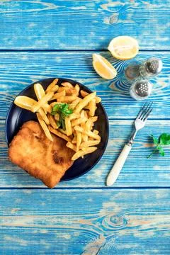 A piece of fried cod with fries on a plate. Stock Photos