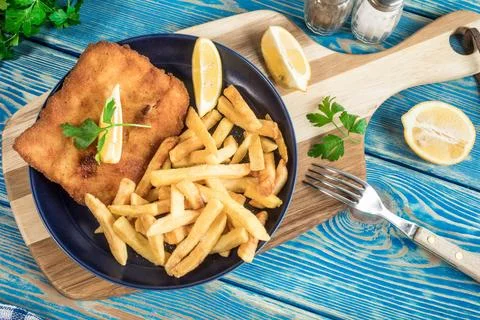 A piece of fried cod with fries on a plate. Stock Photos