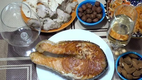 Piece of fried red fish on a plate on a table with appetizers Stock Footage 85083009