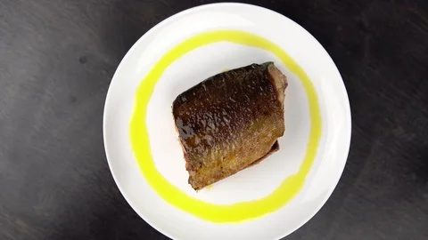 Piece of fried red fish on white plate rotates against black table. Stock Footage 111819231