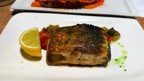 A piece of fried white fish served on a plate with steamed vegetables. 库存影片 329996281