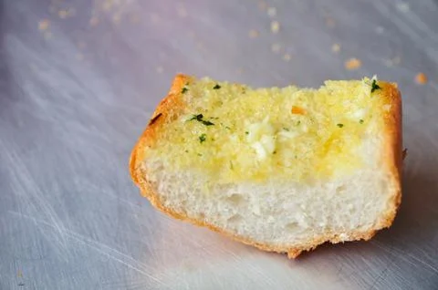 A piece of garlic bread on the shiny surface Stock Photos