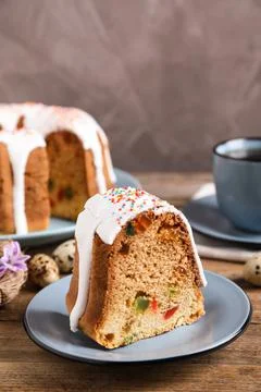 Piece of glazed Easter cake with sprinkles and candied fruits on wooden table Stock Photos