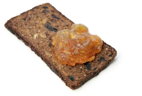 Piece of grain bread with orange jam over white background Stock Photos
