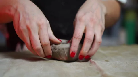 A piece of gray pottery clay on a table with cloth are shapping by female hands Stock Footage 256324665