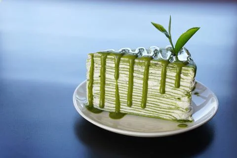 Piece of green tea crape cake on white plate and decorated with fresh tea lea Stock Photos
