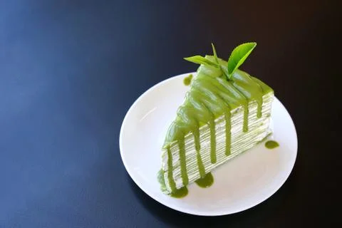 Piece of green tea crape cake on white plate and decorated with fresh tea lea Stock Photos