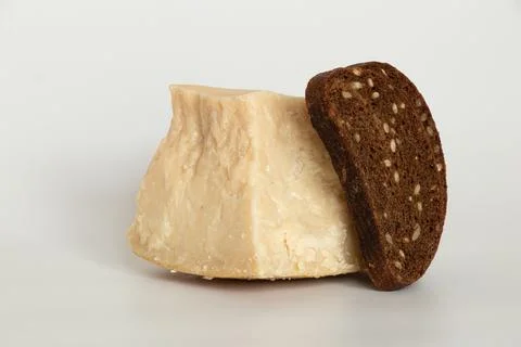 Piece of hard cheese and slice of black bread with seeds on white background Stock Photos