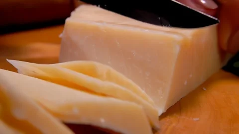 Piece of hard Parmesan cheese cutting by knife into slices Stock-Footage 270942601