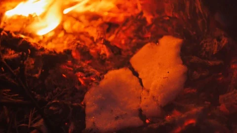 A piece of ice melts in the coals of a fire, a fire in a winter forest close-up Stock Footage 122610580