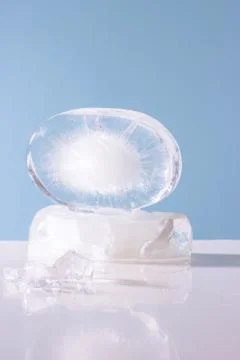 Piece of ice on the table, blue background. Stock Photos
