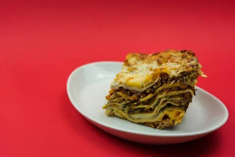 Piece of lasagna on a red background Stock Photos