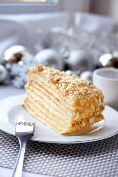 Piece of layer cake with custard and walnuts on a plate with Christmas ball.. Stock Photos
