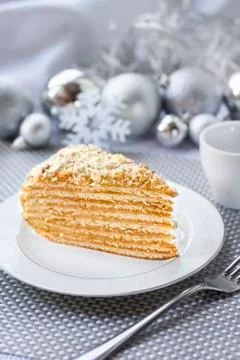 Piece of layer cake with custard and walnuts on a plate with Christmas ball.. Stock Photos