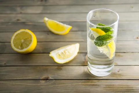 Piece of lemon and mint leaf in transparent glass of mineral water with bubbles Stock Photos