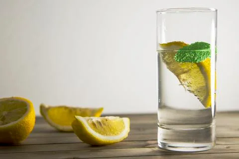 Piece of lemon and mint leaf in transparent glass of mineral water with bubbles Stock Photos