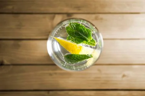 Piece of lemon and mint leaf in transparent glass of mineral water with bubbles Stock Photos