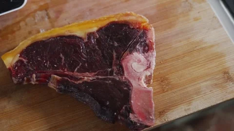 A piece of meat is cut in half and is on a wooden cutting board Stock Footage 305647552