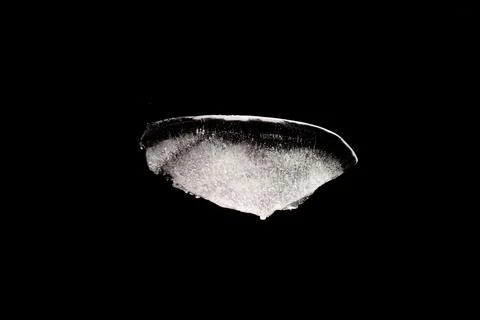 A piece of melting ice on a black background. Ridge-shaped ice close-up Stock Photos