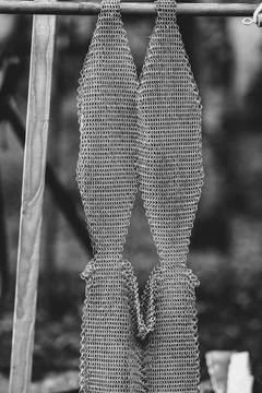 A piece of metal with a pattern on it is hanging from a wooden pole Stock Photos