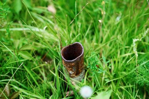 Piece of metal pipe with a sharp edge sticks out of the grass Stock Photos