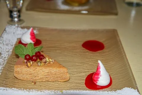 A piece of multi-layered cake with berries, pistachios and cream decoration. Stock Photos