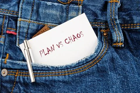 A piece of paper with the words plan vs chaos sits in a denim pocket. A silve 스톡 사진