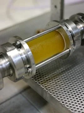 Piece of pipe with beer inside in a beer canning factory Stock Photos
