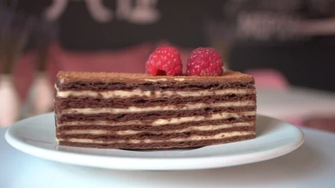 Piece of puff cake honey cake with raspberries rotates on a white plate Stock Footage 117912936