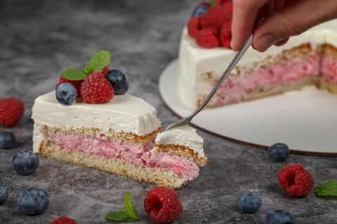 A piece of raspberry mint cake decorated with fresh raspberry and mint leaves 스톡 사진