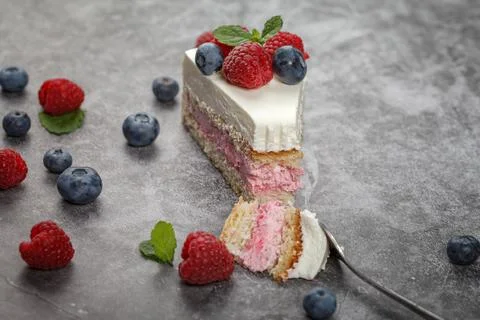 A piece of raspberry mint cake decorated with fresh raspberry and mint leaves 스톡 사진