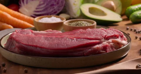 Piece of raw beef meat steak with seasoning ingredients salt pepper and herbs Stock Footage 310063629