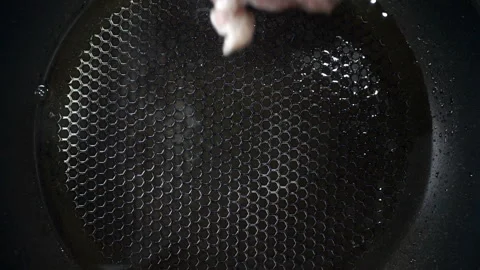 A piece of raw meat falls in slow motion onto a hot pan. Video stock 134732322