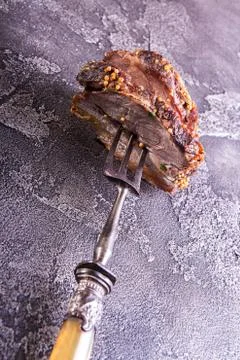 Piece of roasted meat on fork. Cold-boiled baked pork with mustard grains on  Stock Photos