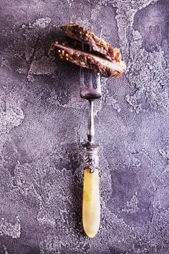Piece of roasted meat on fork. Cold-boiled baked pork with mustard grains on  Stock Photos