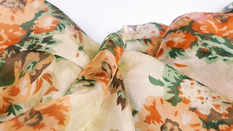 A piece of silk fabric with a floral pattern drops gently onto white background Stock-Footage 337405073