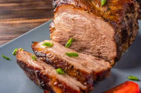 Piece of slow cooked oven-pulled pork shoulder on plate with green onion and Stock Photos