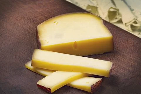 Piece of smoked artisan cheese on wooden base Stock Photos
