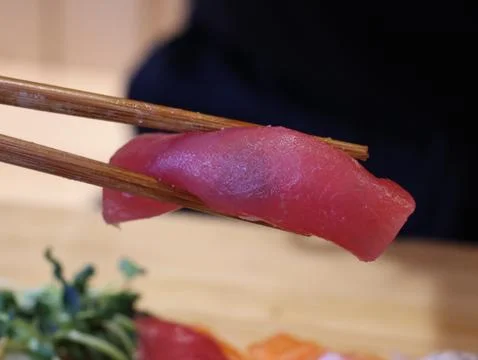 A piece of sushi is being held by chopsticks Stock Photos