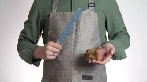 A piece of tasty meat in the hands of a man with a knife, dressed in an apron. Stock Footage 311069339
