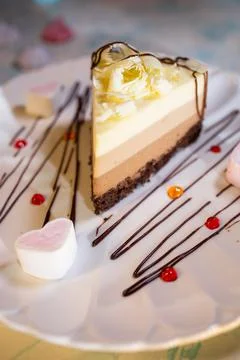 A piece of three-layer chocolate cake on a plate with a beautiful serving Stock Photos