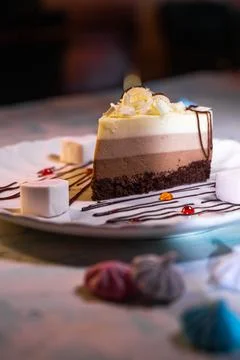 A piece of three-layer chocolate cake on a plate with a beautiful serving Stock Photos